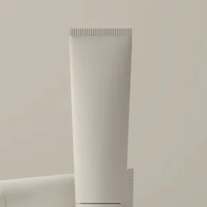 White matte cosmetic tube standing upright beside a second tube lying on a warm grey surface