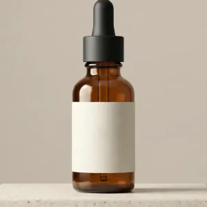 Amber glass dropper bottle with a blank cream label standing on a pale stone plinth